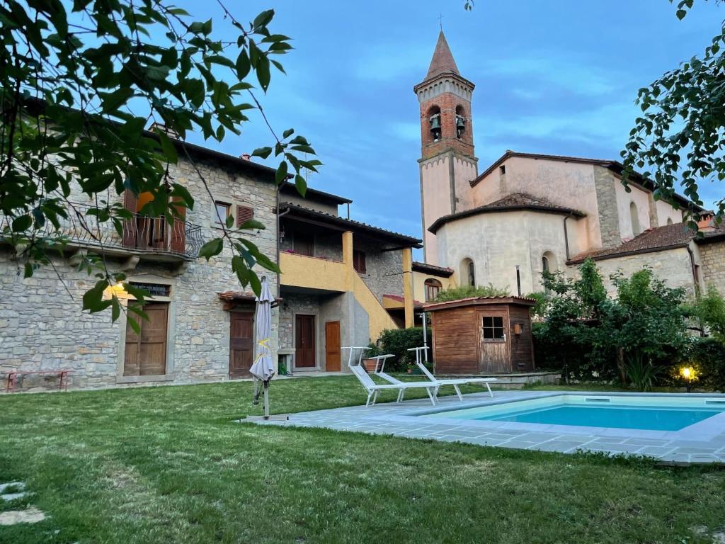a building with a clock tower and a swimming pool at “Da Paolino” in Borgo alla Collina