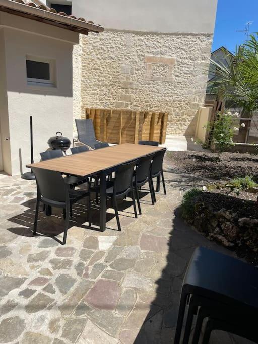 une table et des chaises en bois sur une terrasse dans l'établissement Maison 5 chambres 3sdb en ville avec piscine, à Périgueux