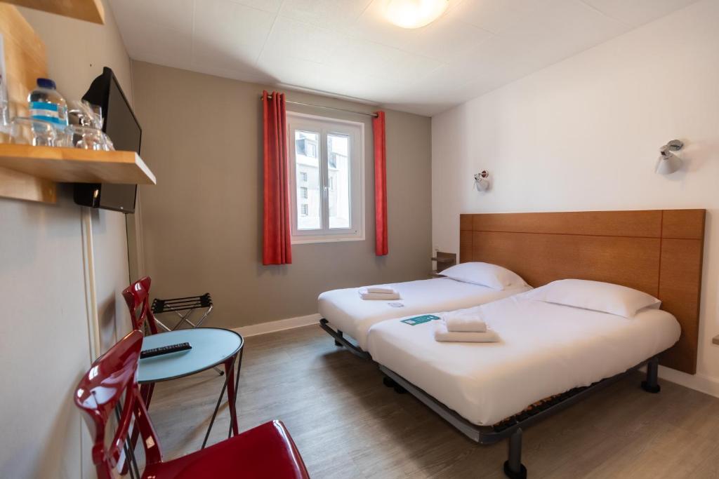 a room with two beds and a table and a window at Gite de la Baie - Morgat in Crozon