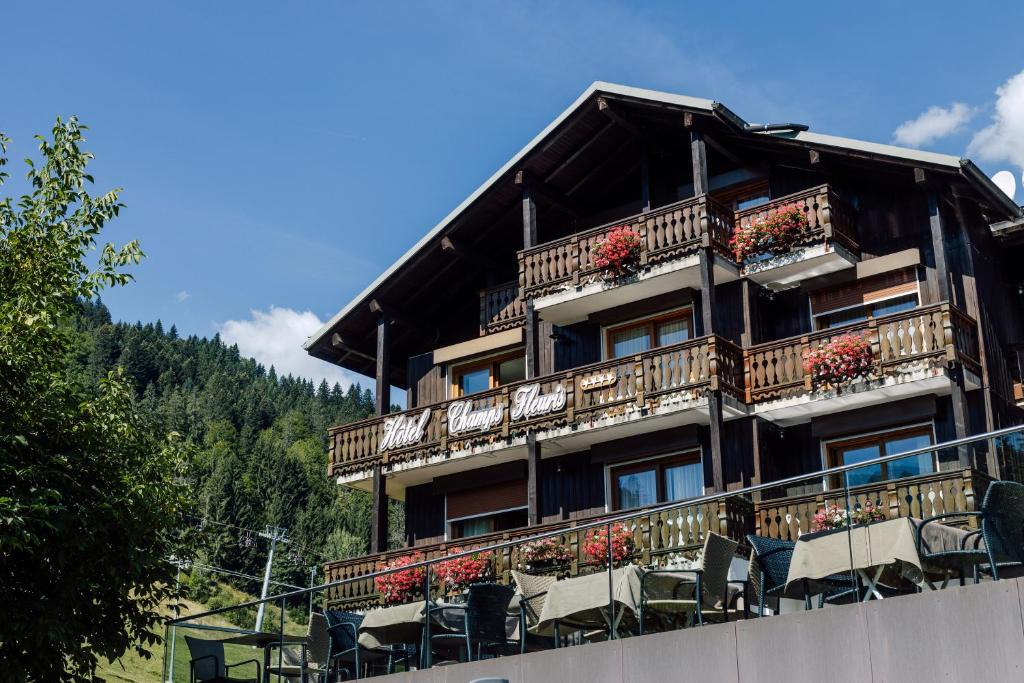 um edifício com cadeiras e flores na varanda em Hôtel Champs Fleuris Morzine em Morzine