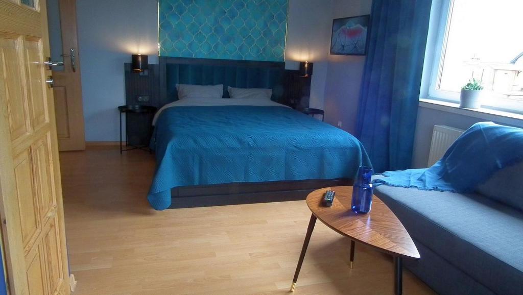 a bedroom with a blue bed and a wooden table at Bursztynek in Stegna