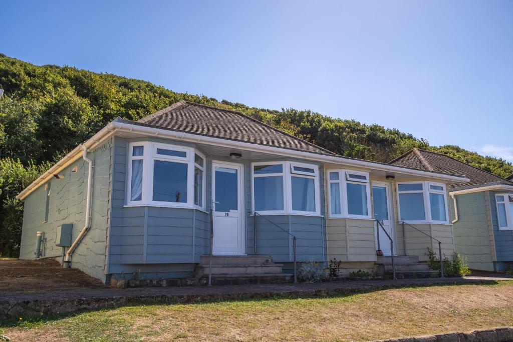 a green house with blue windows at Deluxe Kipling Villa with Sea Views in Bideford