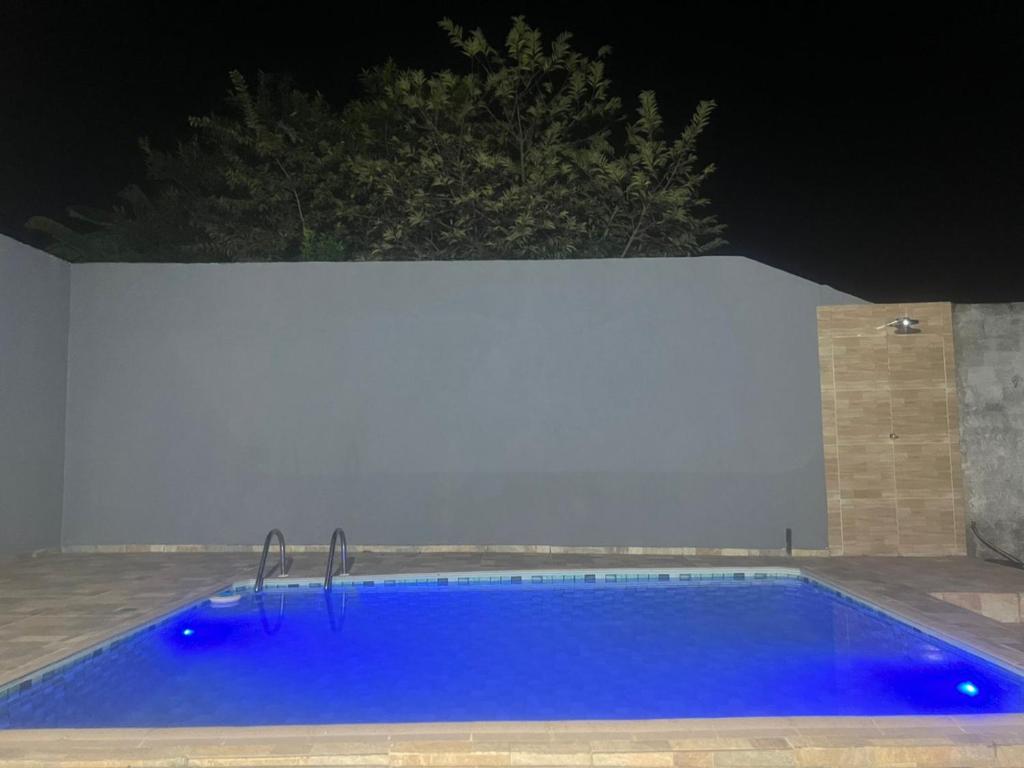 a blue swimming pool at night with a white wall at CASA DE FÉRIAS II in Barra do Garças
