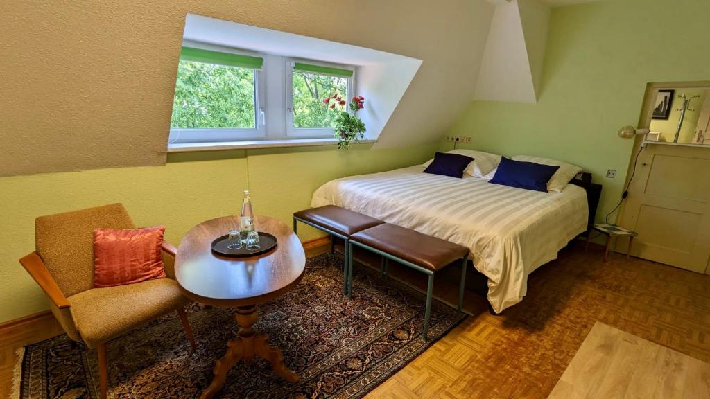 ein Schlafzimmer mit einem Bett, einem Tisch und einem Stuhl in der Unterkunft Große Ferienwohnung mit Loggia und Garten in Cottbus (direkt am Klinikum) in Cottbus