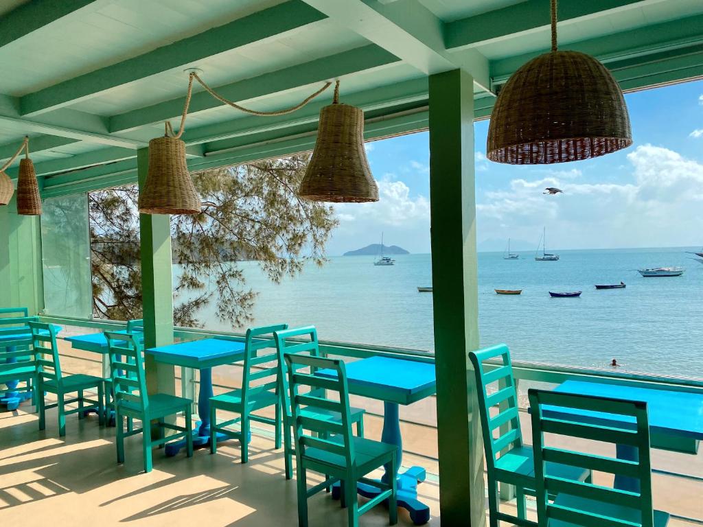 ブジオスにあるBamboo Búzios Hostelの青いテーブルと椅子が備わる海の景色を望むレストラン