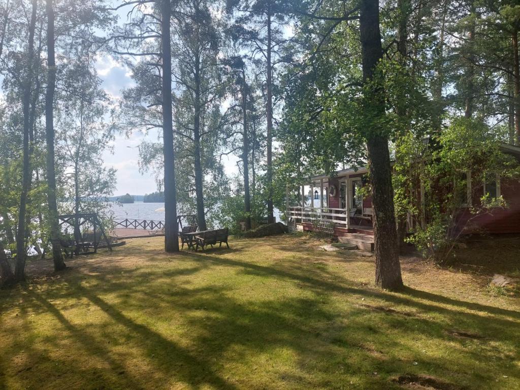 a park with a house and a bench in the grass at Lakeside Lea, rantamökki 