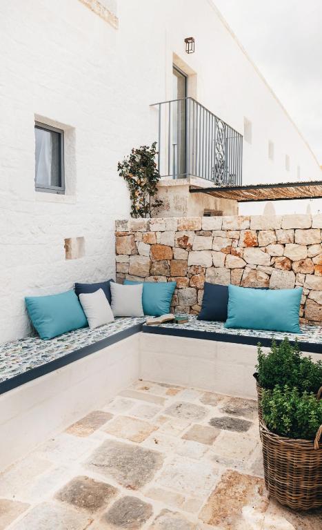 a patio with blue pillows on a stone wall at Masseria Auraterrae in Polignano a Mare