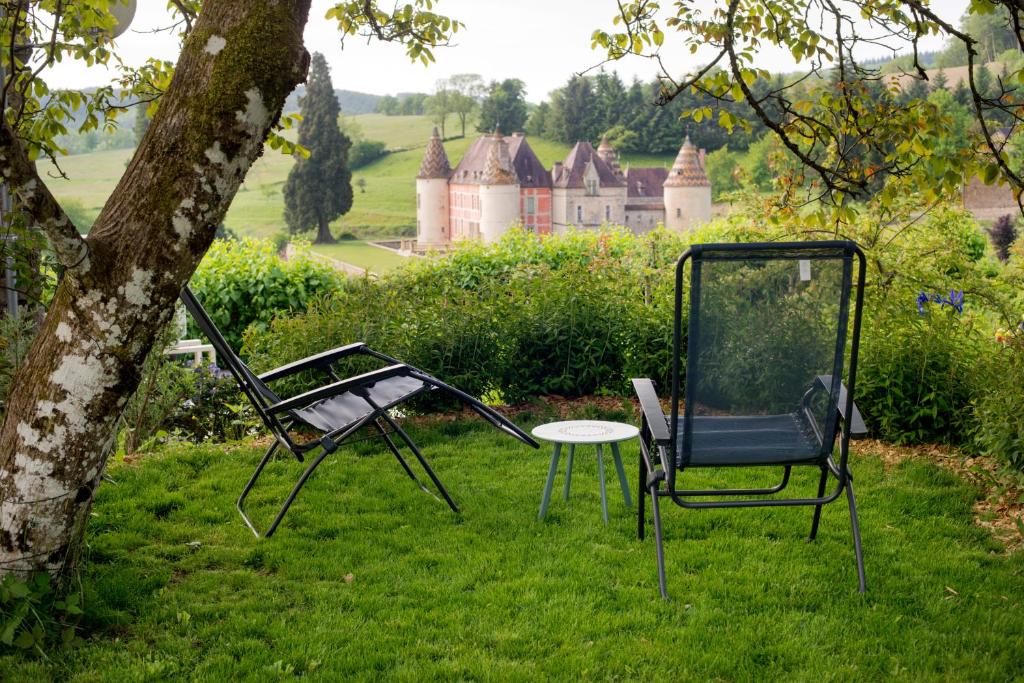 two chairs and a table in front of a house at Maison de vacances Les Mésanges, à Ménessaire in Ménessaire