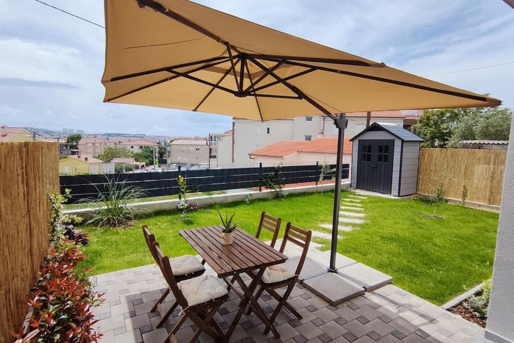 a table and chairs with an umbrella on a patio at Salona Garden Apartman in Solin
