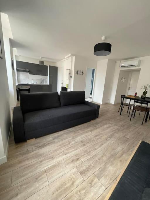 ein Wohnzimmer mit einem schwarzen Sofa und einem Tisch in der Unterkunft Appartement1 neuf climatisée in Blaye