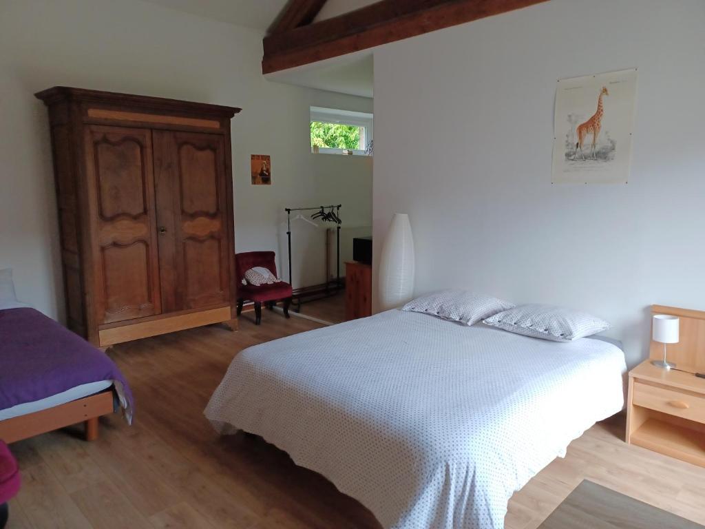 a bedroom with a white bed and a wooden cabinet at 2 chambres privées au calme à la Maison des Bambous in Dijon
