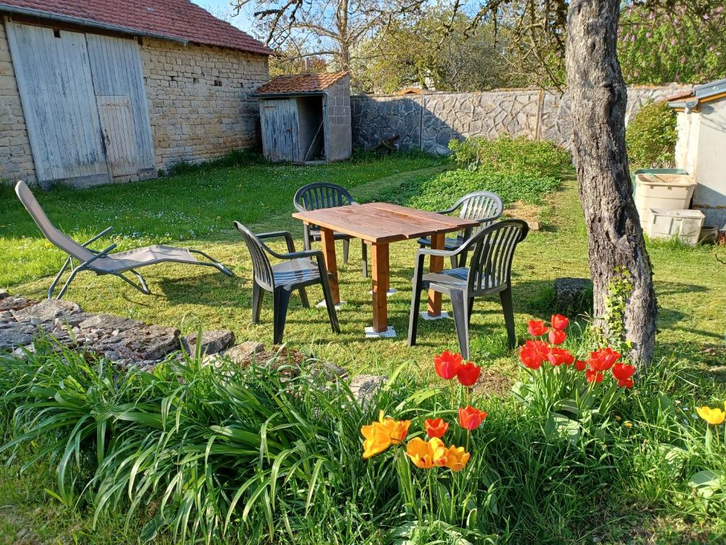 a table and chairs in a yard with flowers at 2 chambres privées au calme à la Maison des Bambous in Dijon