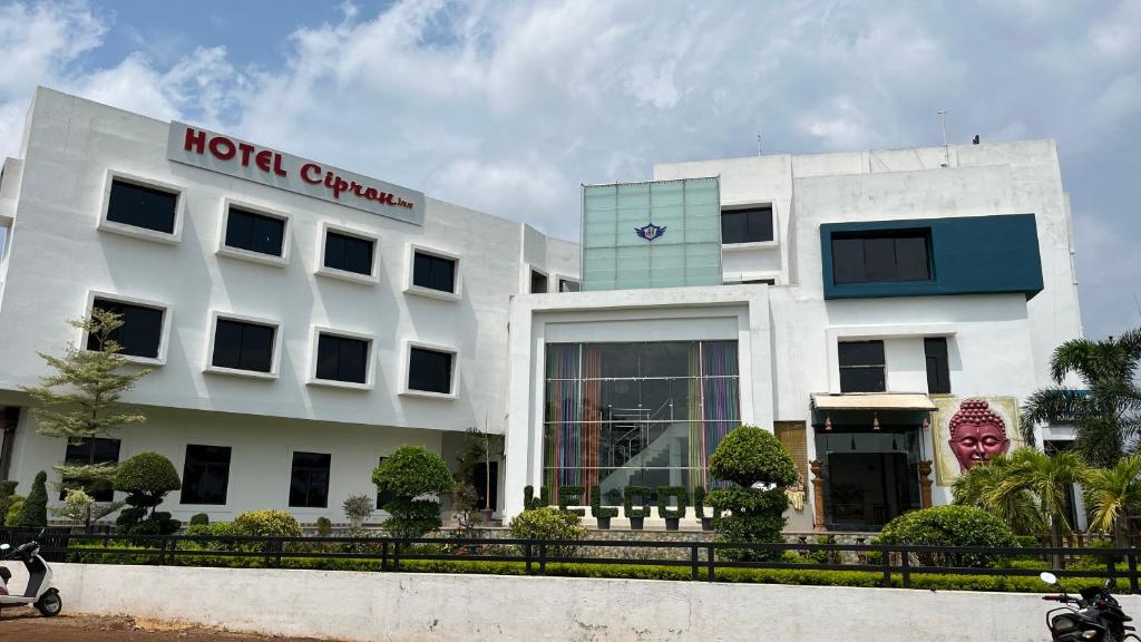 a white building with a sign on it at Hotel Cipron Inn in Udala
