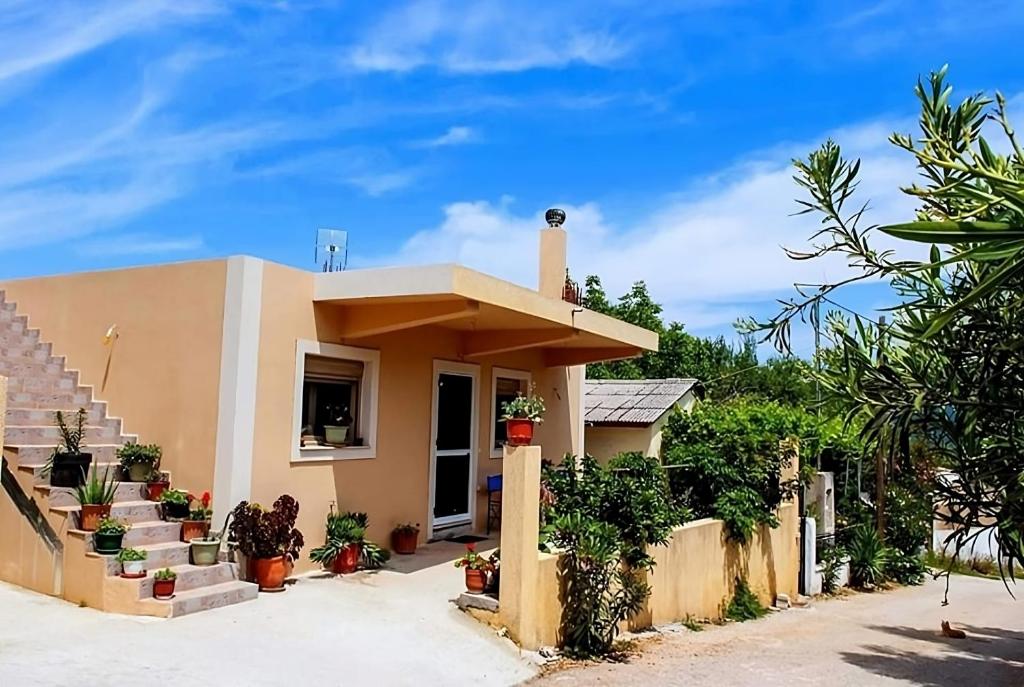 een huis met een veranda en een trap ervoor bij Flamiatos Garden Cottages in Pouláta