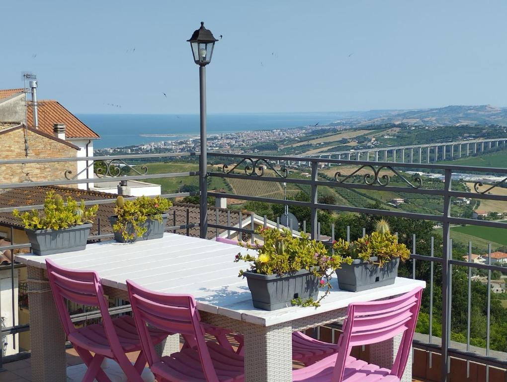 a table with purple chairs and flowers on a balcony at La Rue in Tortoreto Lido