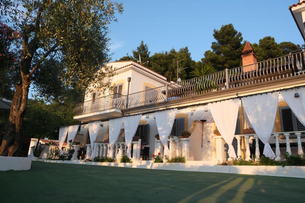 um edifício branco com uma varanda e um relvado verde em Valle dei Greci Rooms em Peschici