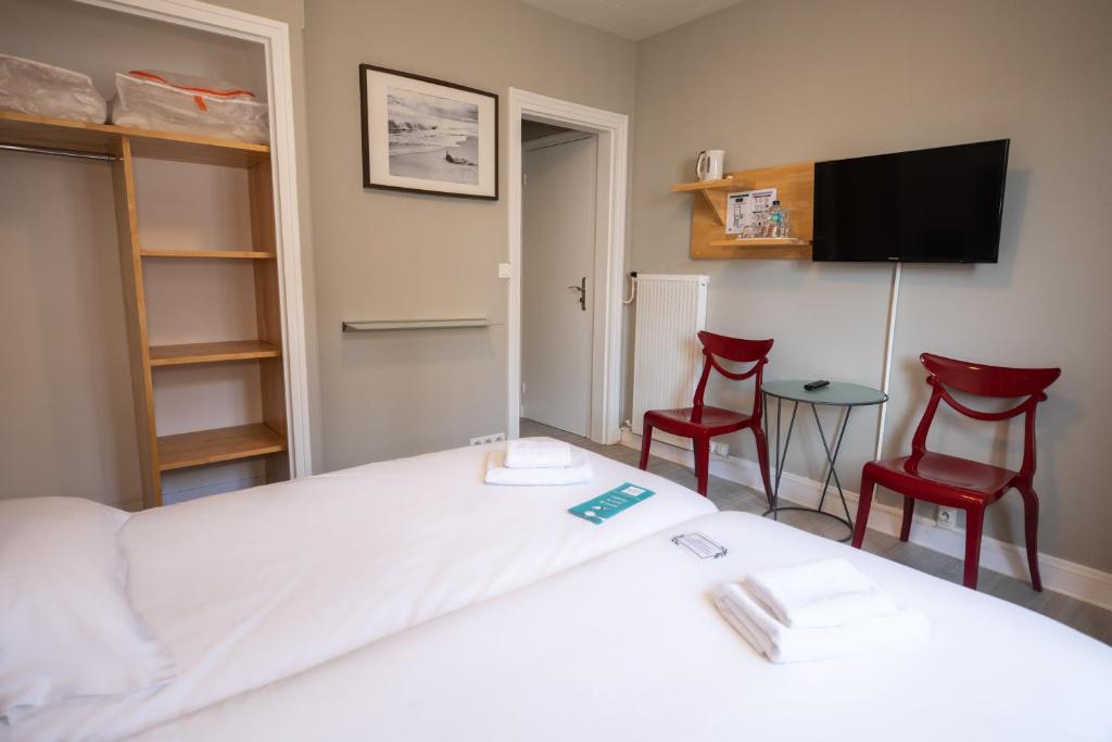 a bedroom with a bed and two red chairs at Gite de la Baie - Morgat in Crozon