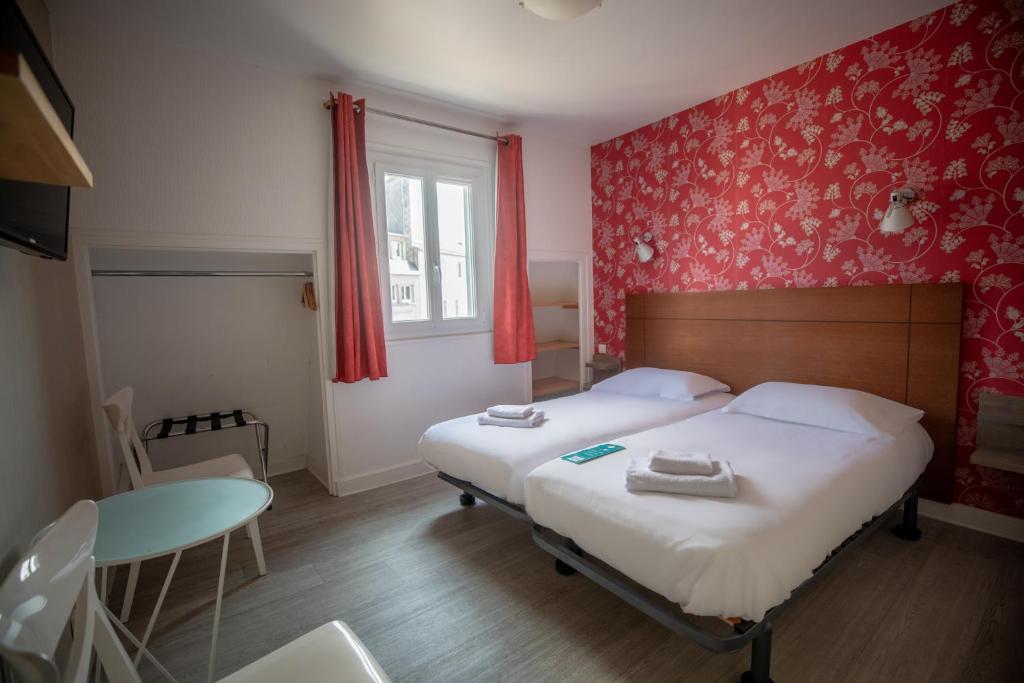 a bedroom with two beds and a table and a window at Gite de la Baie - Morgat in Crozon