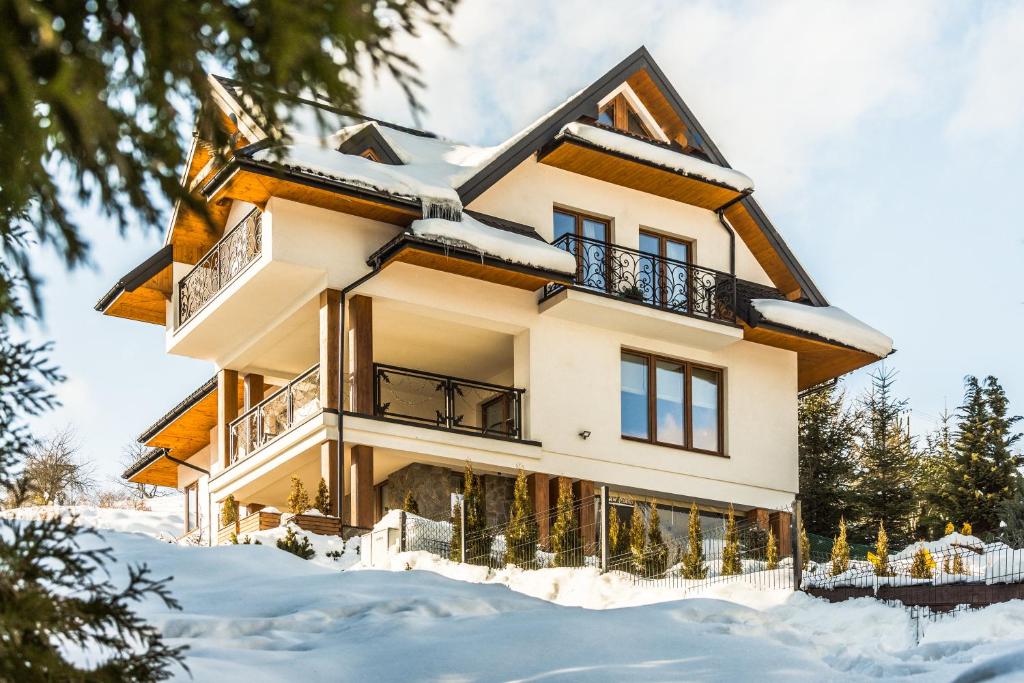 una casa con nieve en el suelo delante de ella en Willa Golasówka, en Muszyna