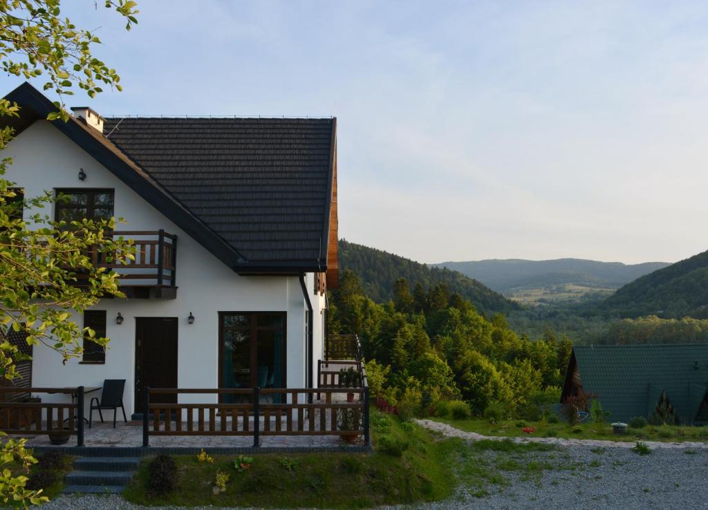 biały dom z gankiem i balkonem w obiekcie Apartamenty Wilcza Knieja w Zawozie