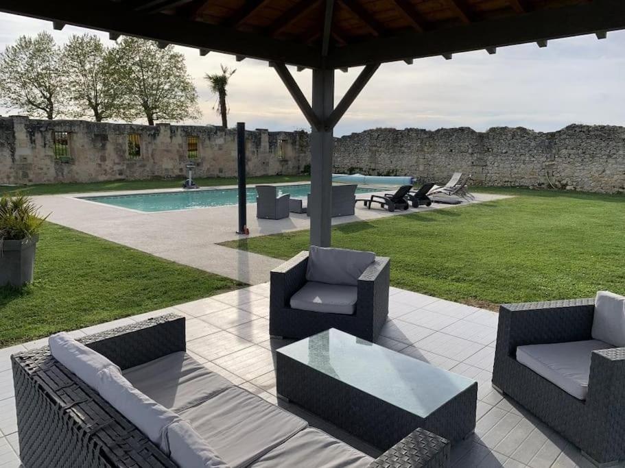 eine Terrasse mit 2 Stühlen, einem Tisch und einem Pool in der Unterkunft Gîte l'ombrière in Saint-Caprais-de-Bordeaux