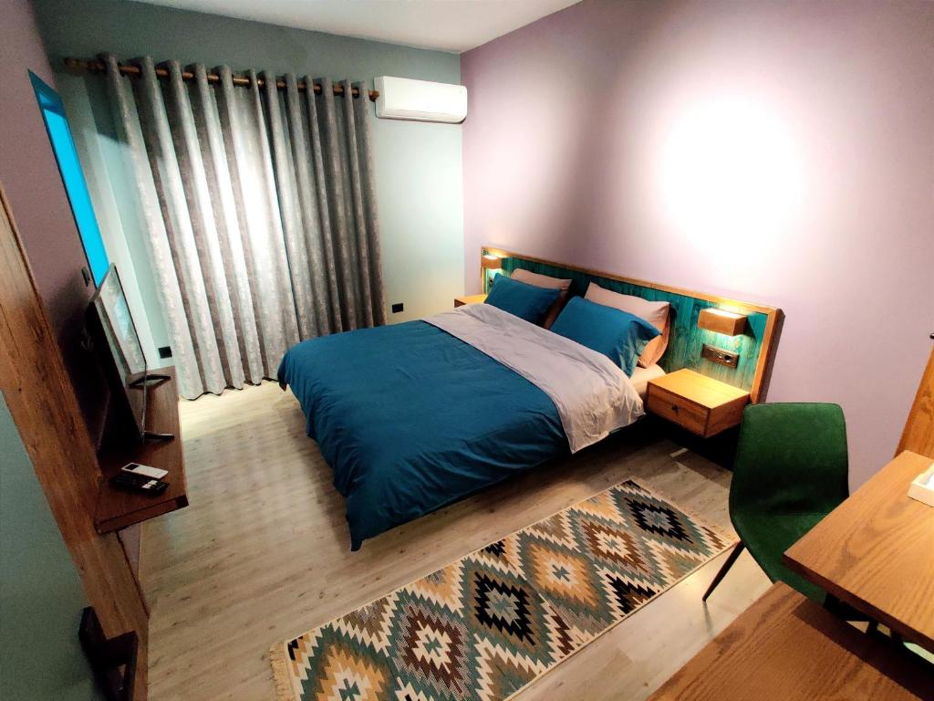 una camera con letto blu e televisore di Piro's Cozy Rooms - City Centre a Korçë
