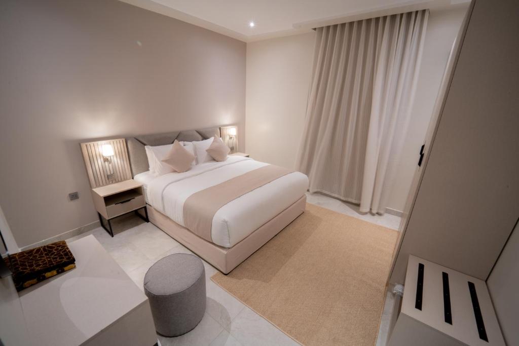 a white bedroom with a bed and a table at جوهرة الشرق للشقق المخدومة in Al Khobar