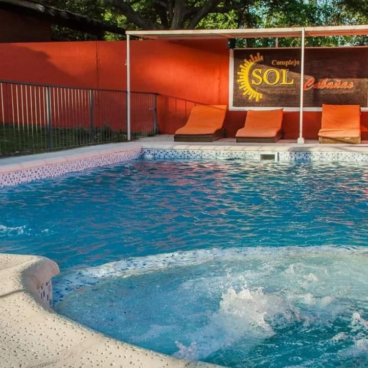 a swimming pool with orange chairs next to a building at Complejo Sol in Villa Carlos Paz