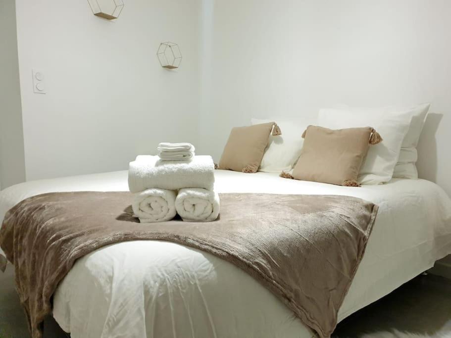 a white bed with two towels on top of it at Le Cottage in Pamiers