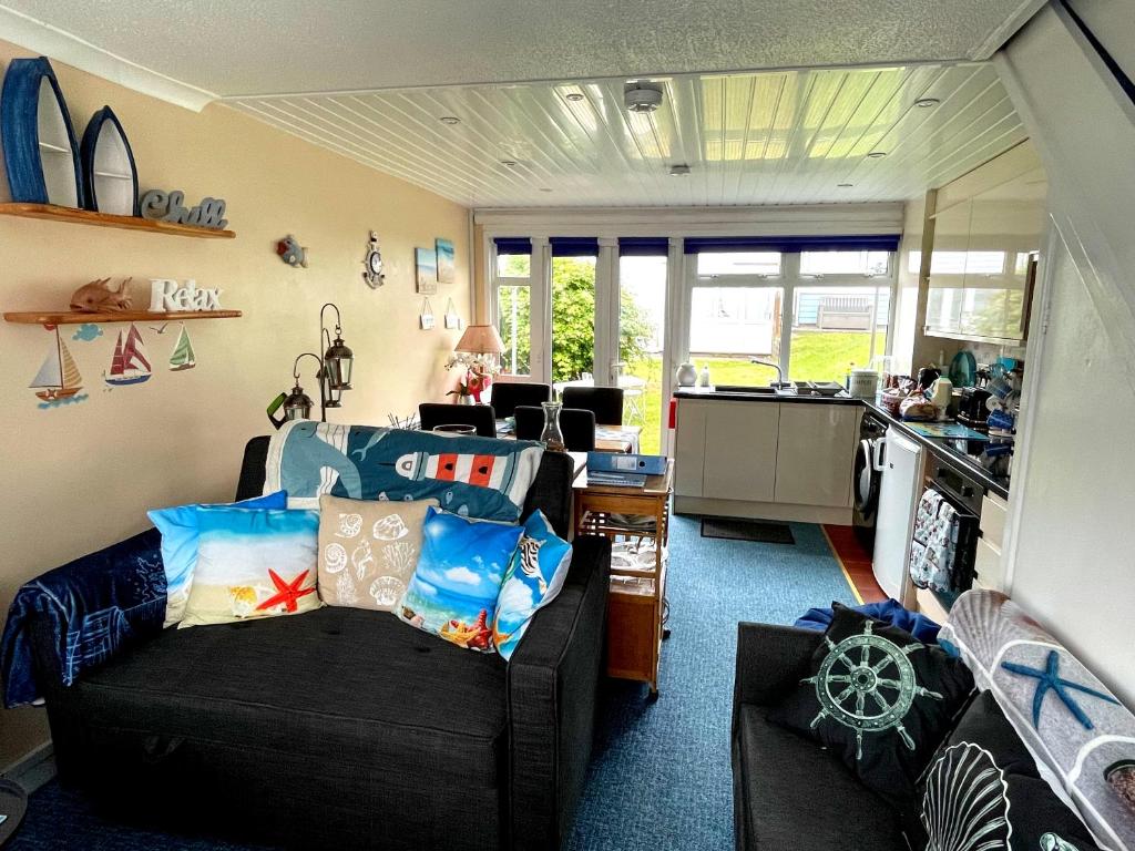 a living room with two couches and a kitchen at Cariad Beach House in Pembrokeshire
