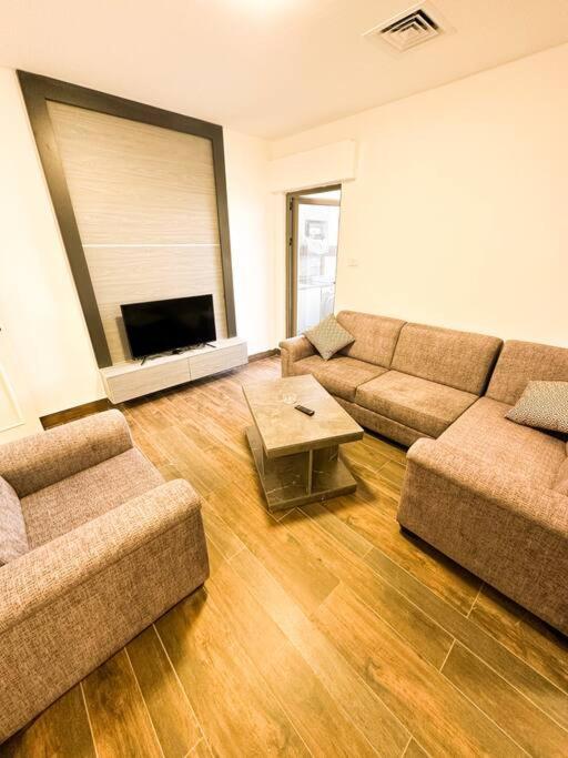 a living room with two couches and a flat screen tv at central apartment for rent 28 in Umm Uthainah