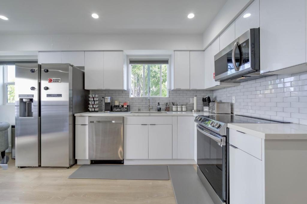 a kitchen with white cabinets and stainless steel appliances at Modern Apartment in Studio City in Los Angeles