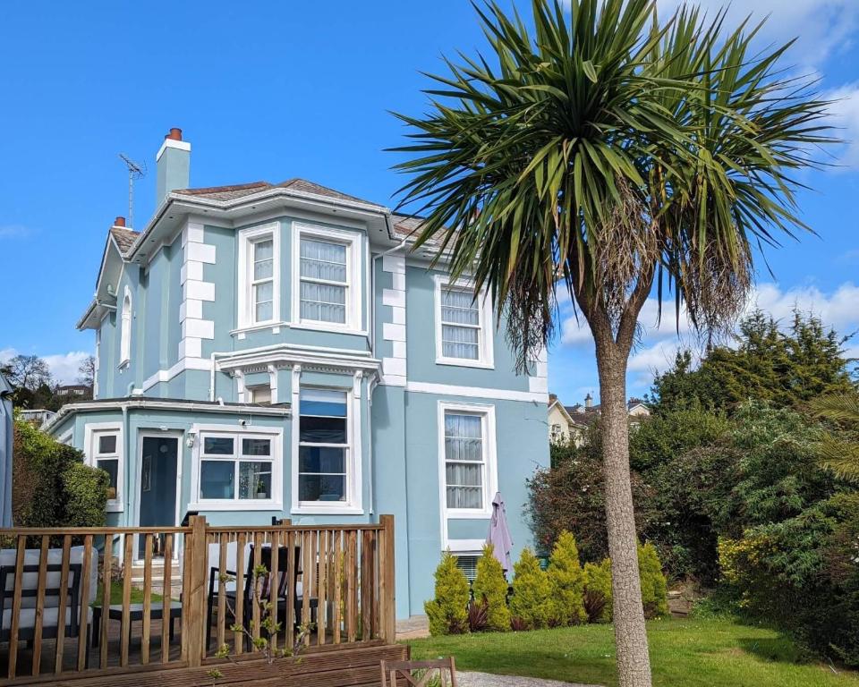 a blue house with a palm tree in front of it at Villa Marina in Torquay