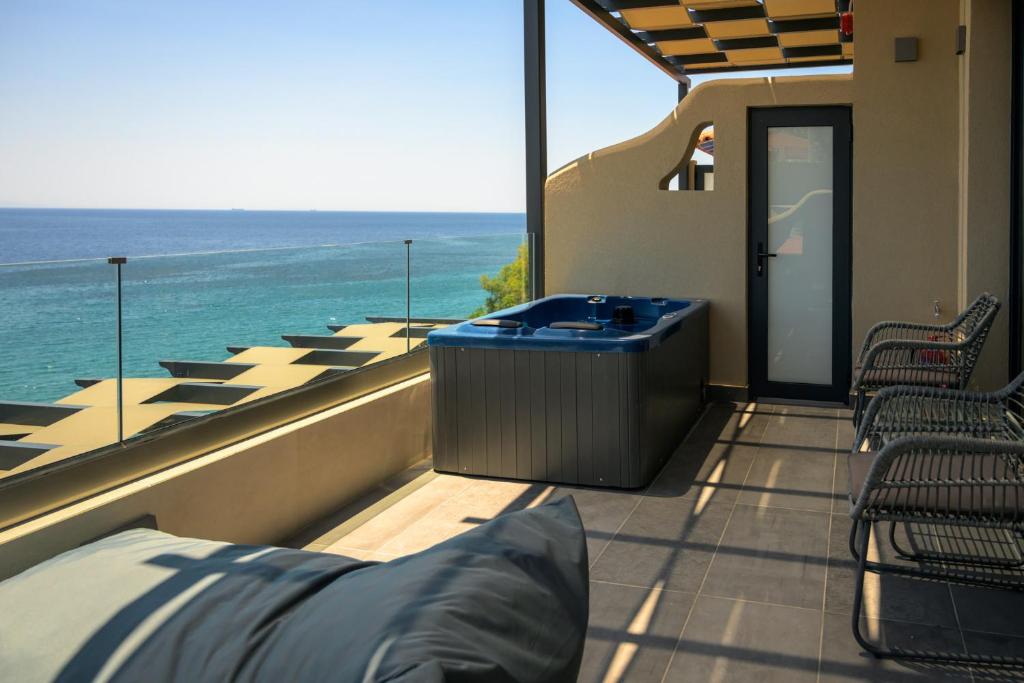 bañera de hidromasaje en el balcón de una casa con vistas al océano en Olive Green Studios and Apartments en Plomari