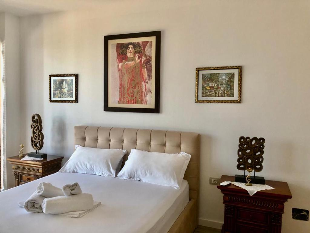 a bedroom with a bed and a painting on the wall at Rahoni Park & Suites in Dhërmi