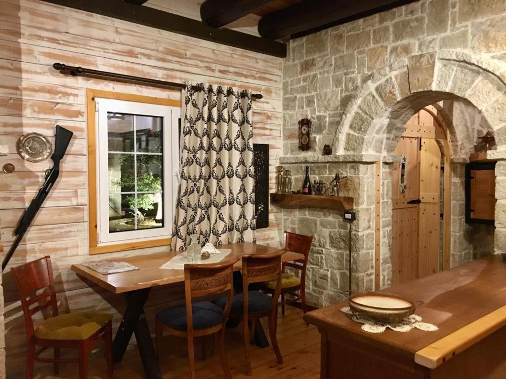 a dining room with a table and a stone wall at Rahoni Park & Suites in Dhërmi