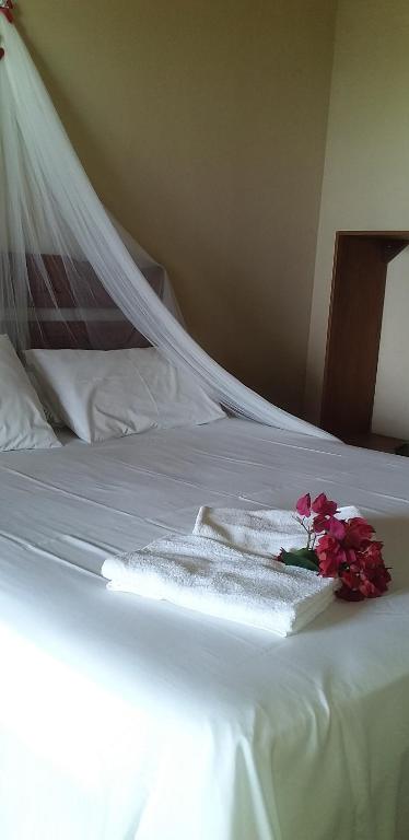 - un lit blanc avec des serviettes et des fleurs dans l'établissement Village Lagoinha Ceará, à Paraipaba