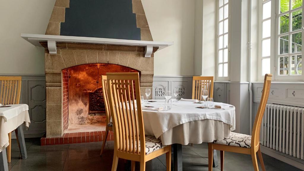 une salle à manger avec une table et une cheminée dans l'établissement Hôtel De France - Restaurant L'insolite, à Douarnenez