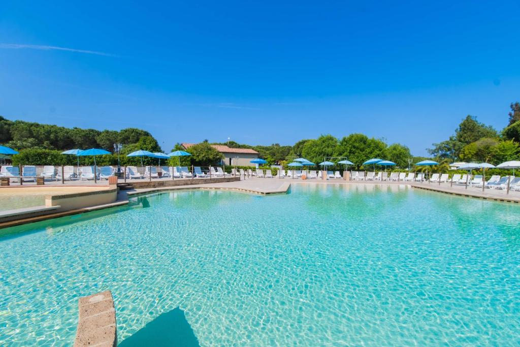 a large swimming pool with chairs and umbrellas at Camping Le Palme in Marina di Bibbona