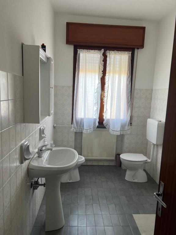 een badkamer met een wastafel, een toilet en een raam bij Casa Gazzola in Crespano del Grappa