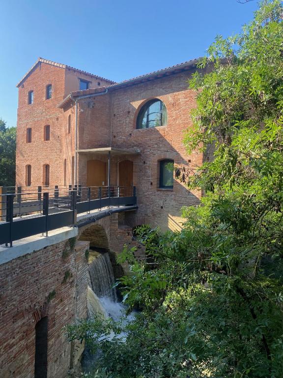 un bâtiment en briques avec un pont sur une rivière dans l'établissement LE MOULIN DE LA FLAMBERE, à Toulouse