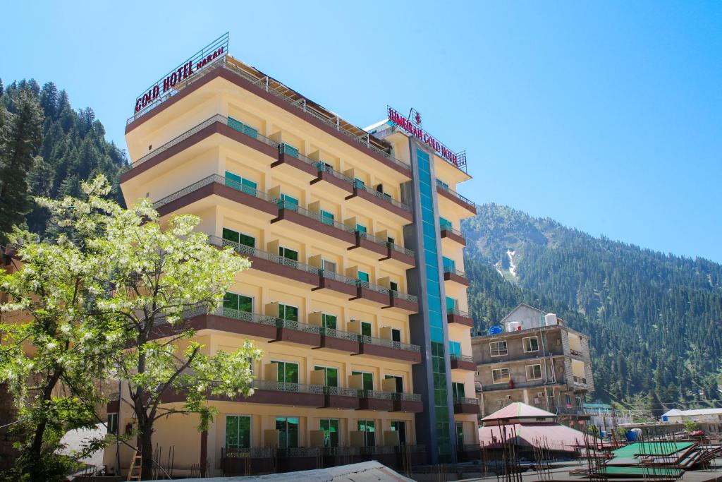 a large yellow building in front of a mountain at Jovial Gold Naran in Nārān