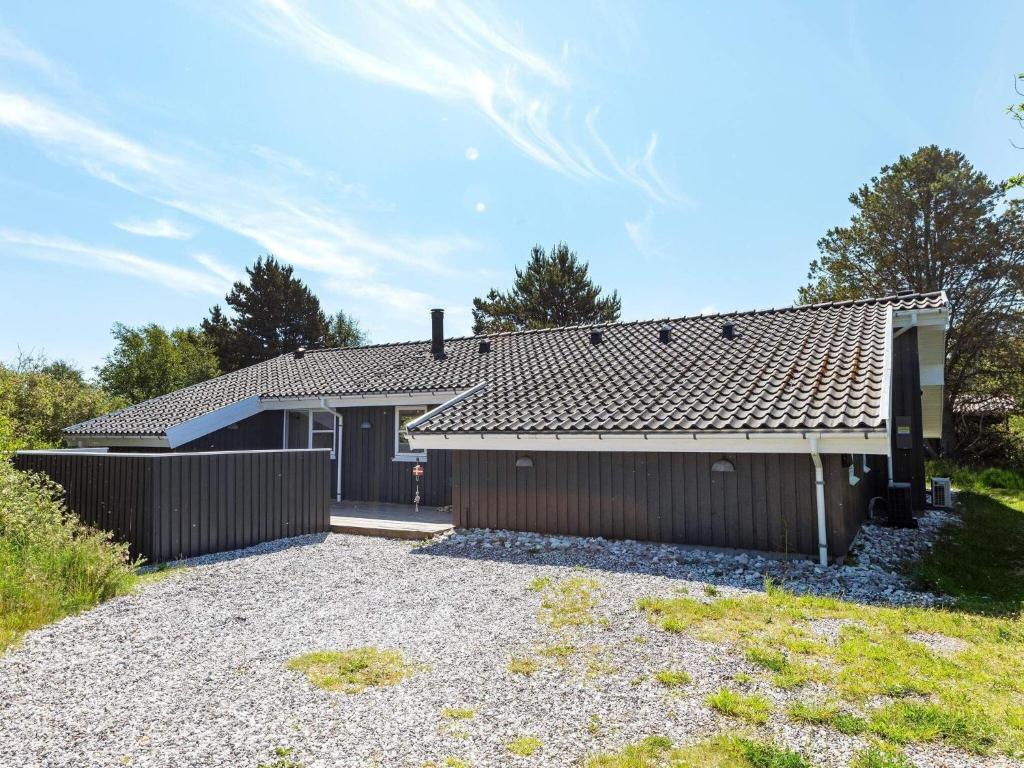 a house with a fence and a gravel driveway at Four-Bedroom Holiday home in Fjerritslev 3 in Torup Strand