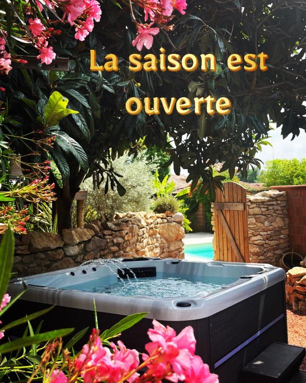 un jacuzzi dans un jardin avec un panneau indiquant « la salson est converge » dans l'établissement Tiny House Piscine et Spa, à Gaillac