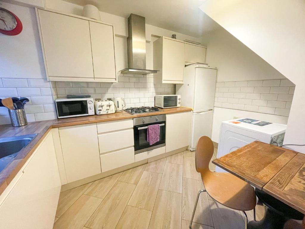 a kitchen with white appliances and a wooden table at Flat 4, Kingsbury house in London
