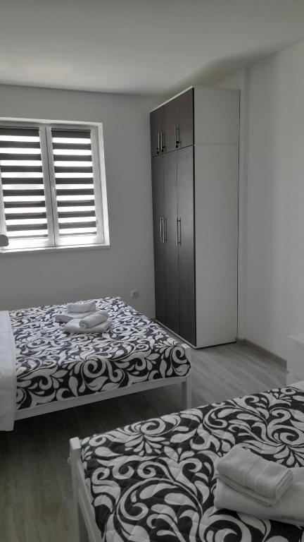 a bedroom with two beds and a cabinet and windows at Apartman Stamenković in Veliko Gradište