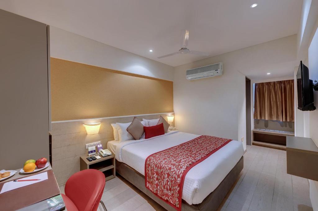 ein Hotelzimmer mit einem Bett und einem roten Stuhl in der Unterkunft Click Hotel Vadodara 2 Mins from Railway Station in Vadodara