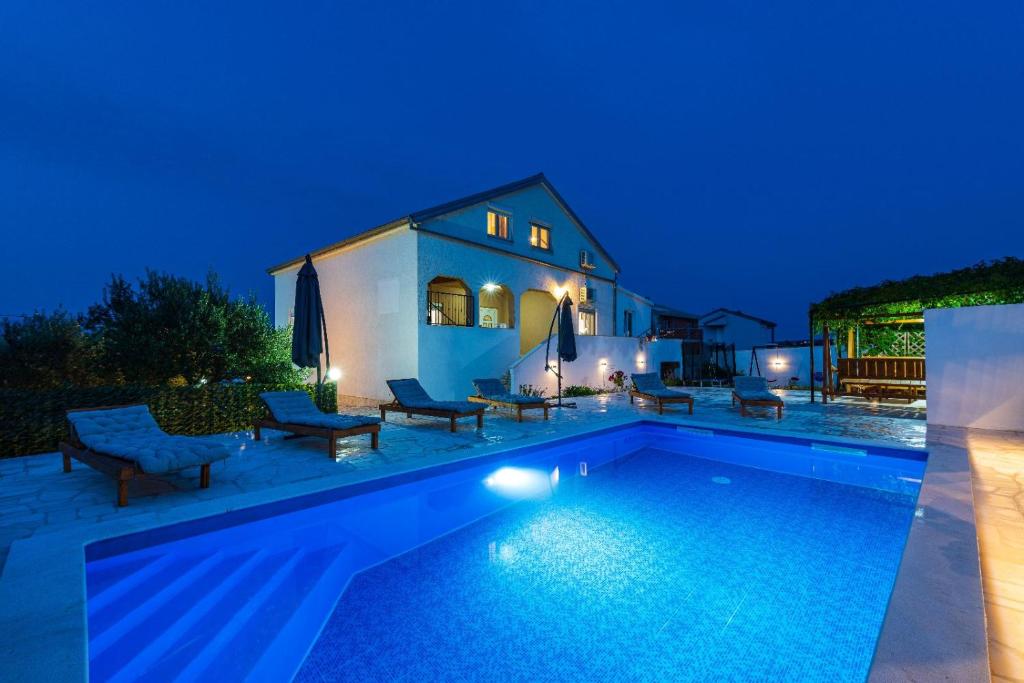 a swimming pool in front of a house at night at Villa Gabi in Pridraga