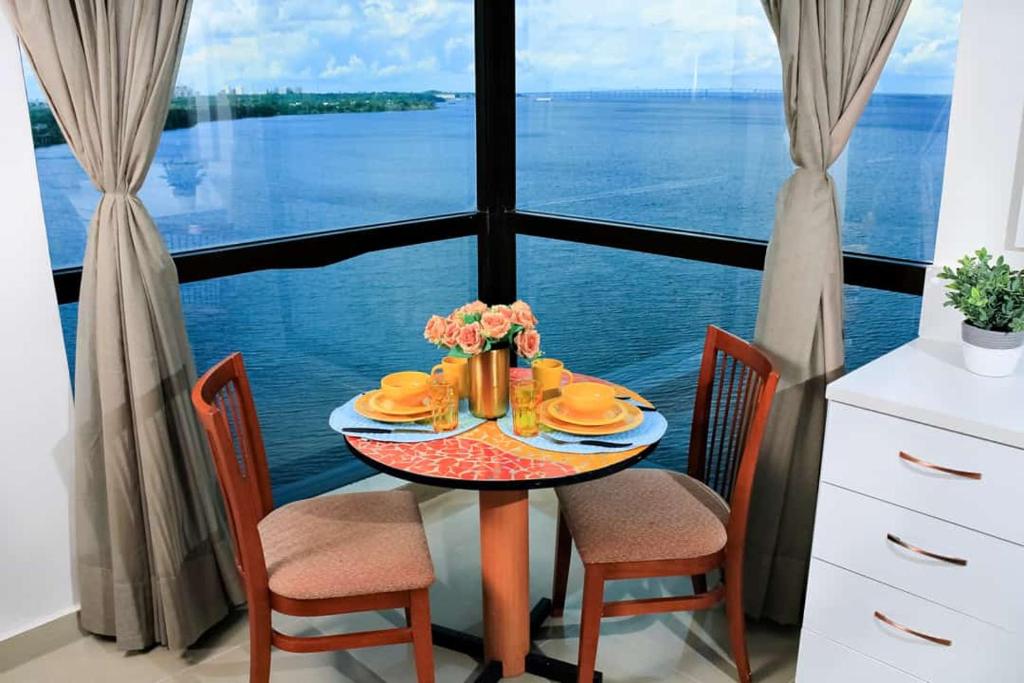 a table with a plate of food and a view of the water at Tropical Executive 1305 with VIEW in Manaus