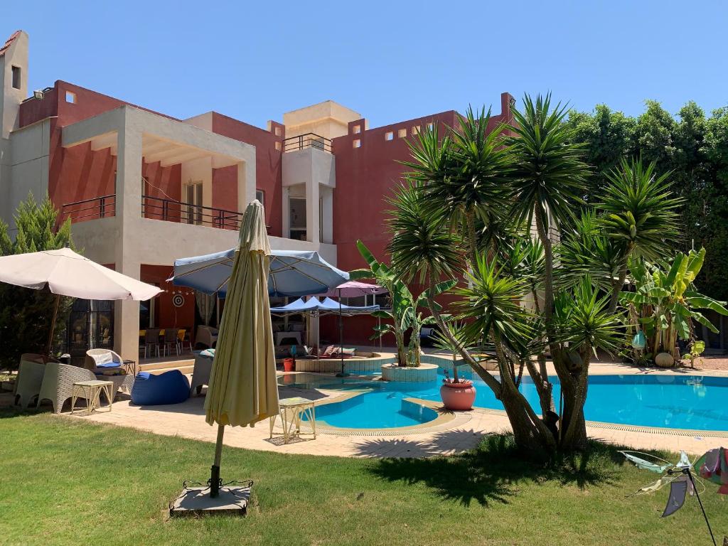 un patio con sombrilla y piscina en Perfect family vacation house, en King Mariout